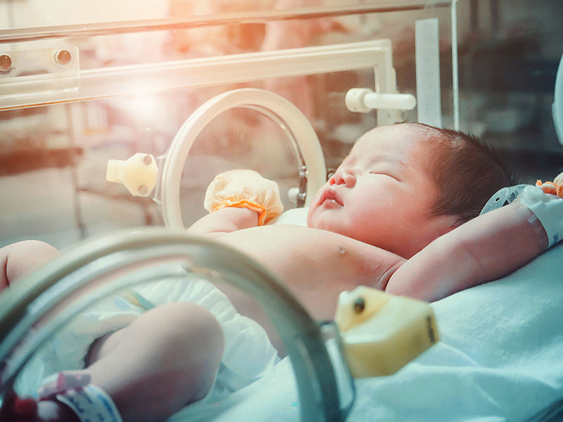 Newborn baby girl inside incubator in hospital post delivery room